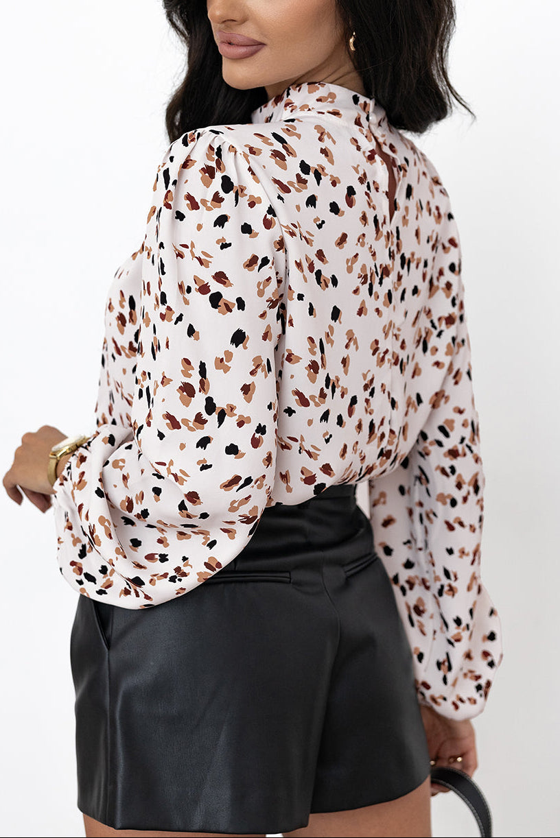 Woman wearing a patterned blouse and black shorts on a white background